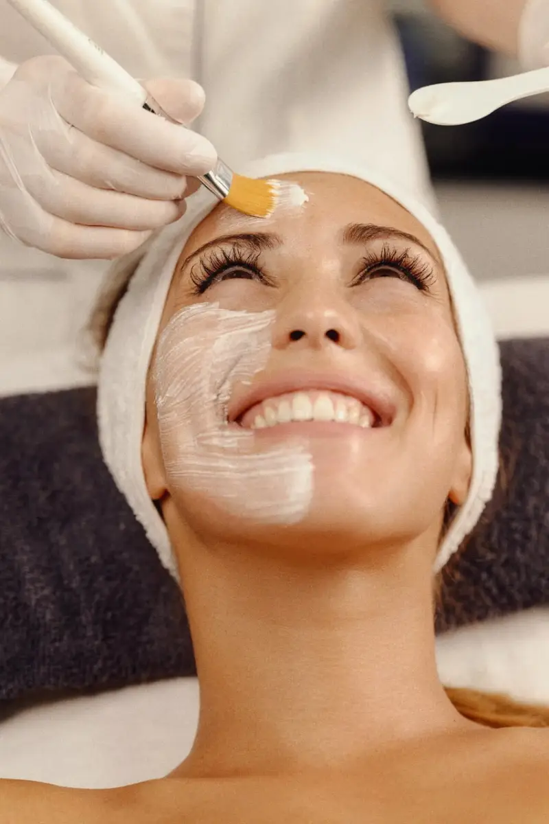 Gesichtsreinigung und Schönheitspflege - Kosmetikerin von Sense of Beauty trägt Maske auf eine lächelnde Frau auf in Kosmetikstudio in Braunschweig.