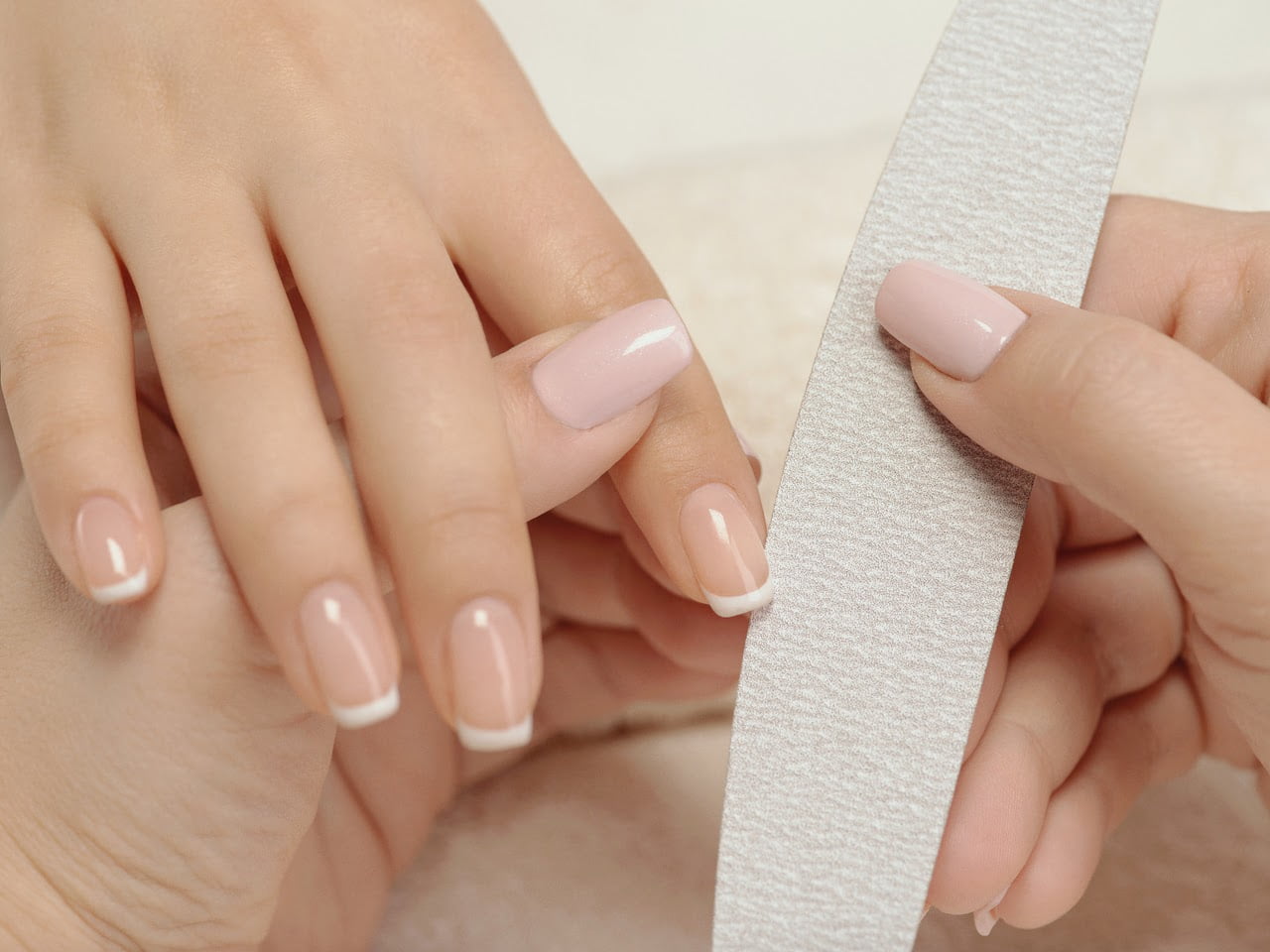 Frau erhält eine professionelle Maniküre mit Nagelfeile in einem Schönheitssalon.